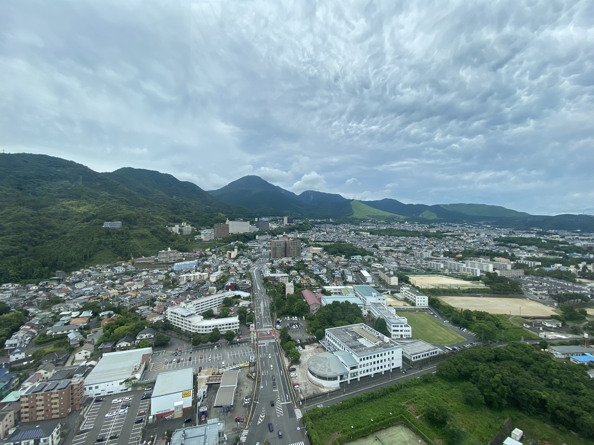 Beppu city aerial panoramic view from hill town buildings mountains clouds summer