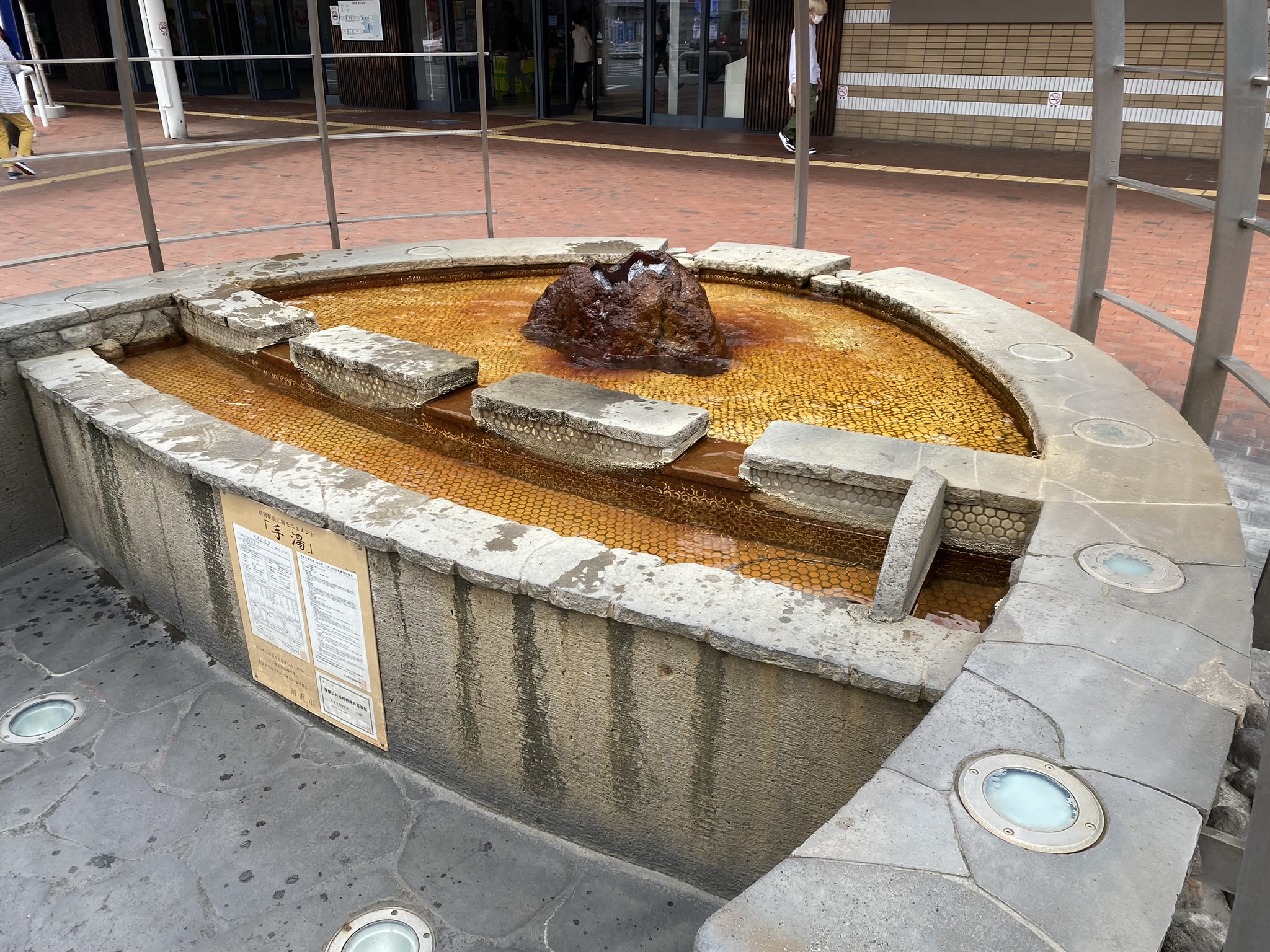 Stone monument shaped like hot spring mud pool at Beppu Station plaza