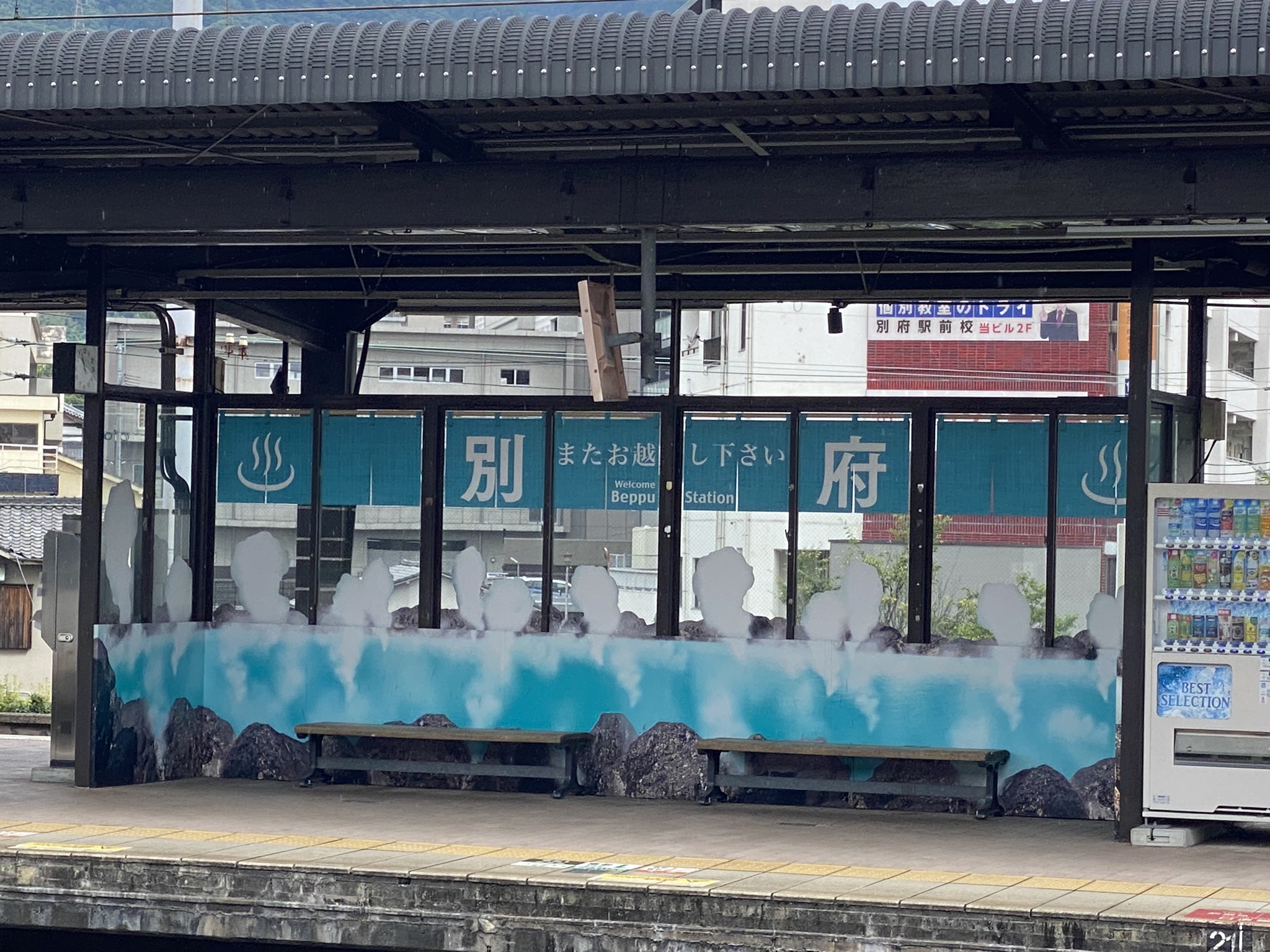 Beppu Station platform with hot spring themed bench and wall art showing steam