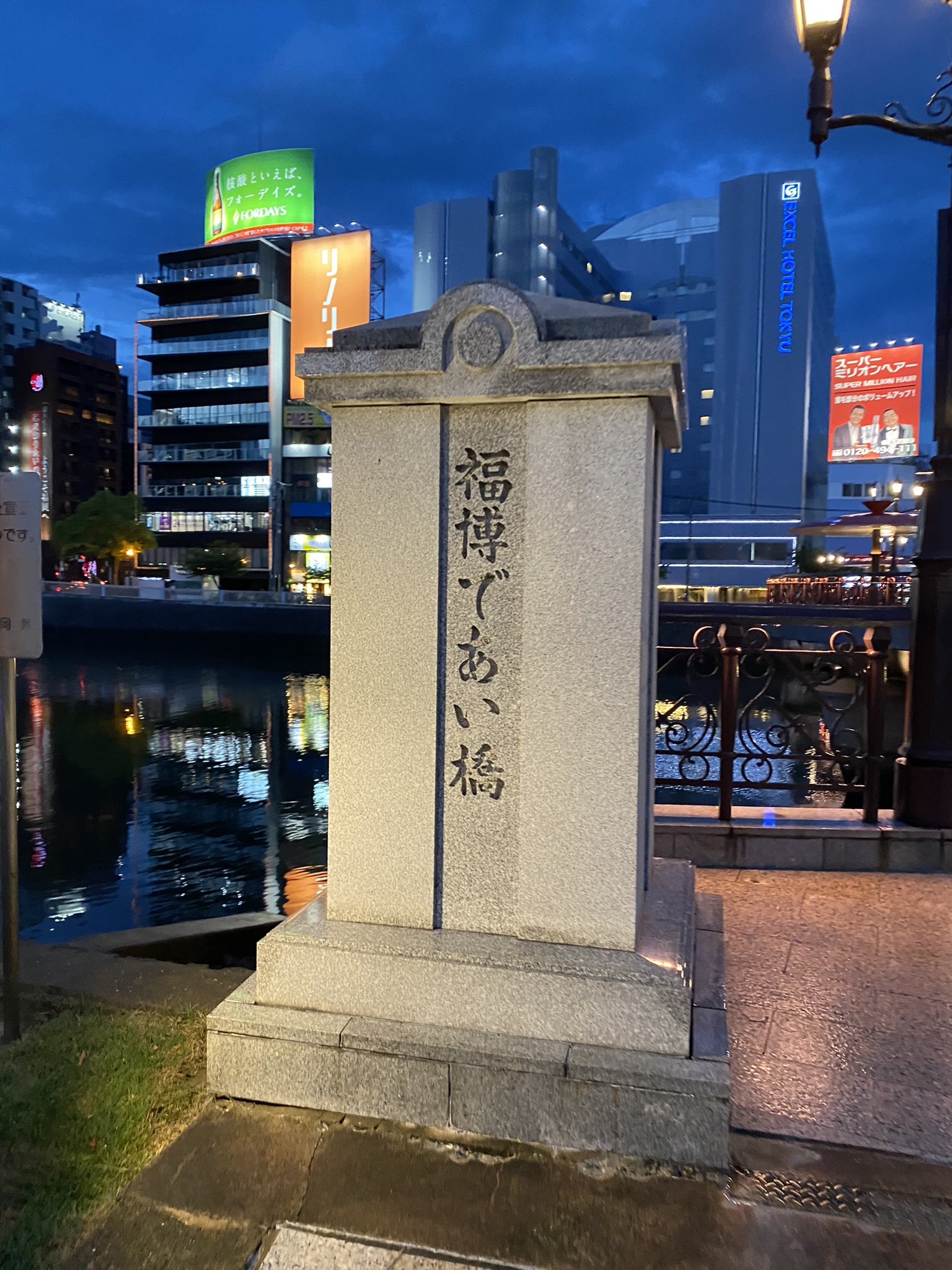 Stone sign for Fukuhaku Deai Bashi pedestrian bridge at Nakasu Fukuoka illuminated at night