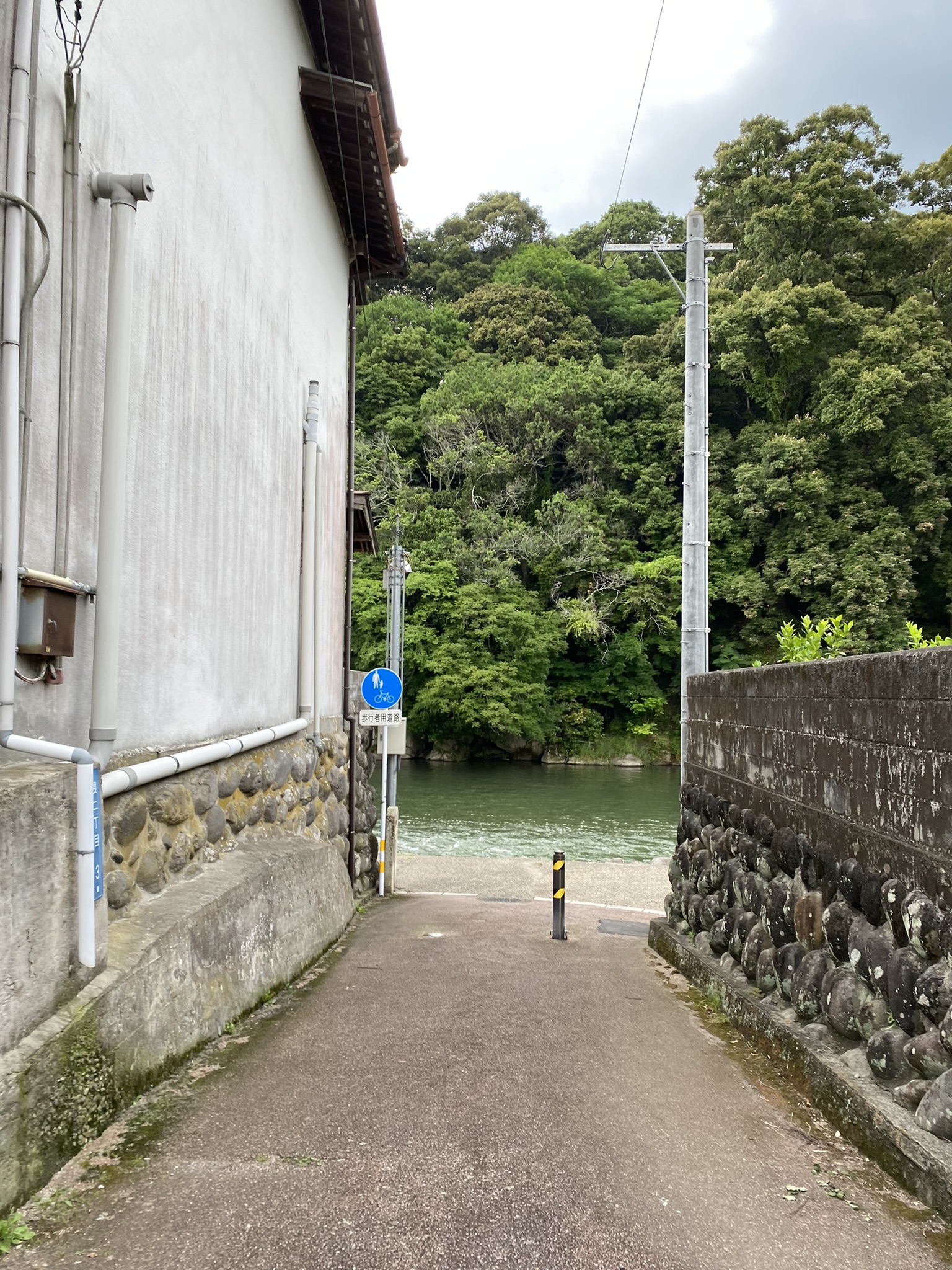 Hita city narrow alley between buildings glimpse of Mikuma river green trees