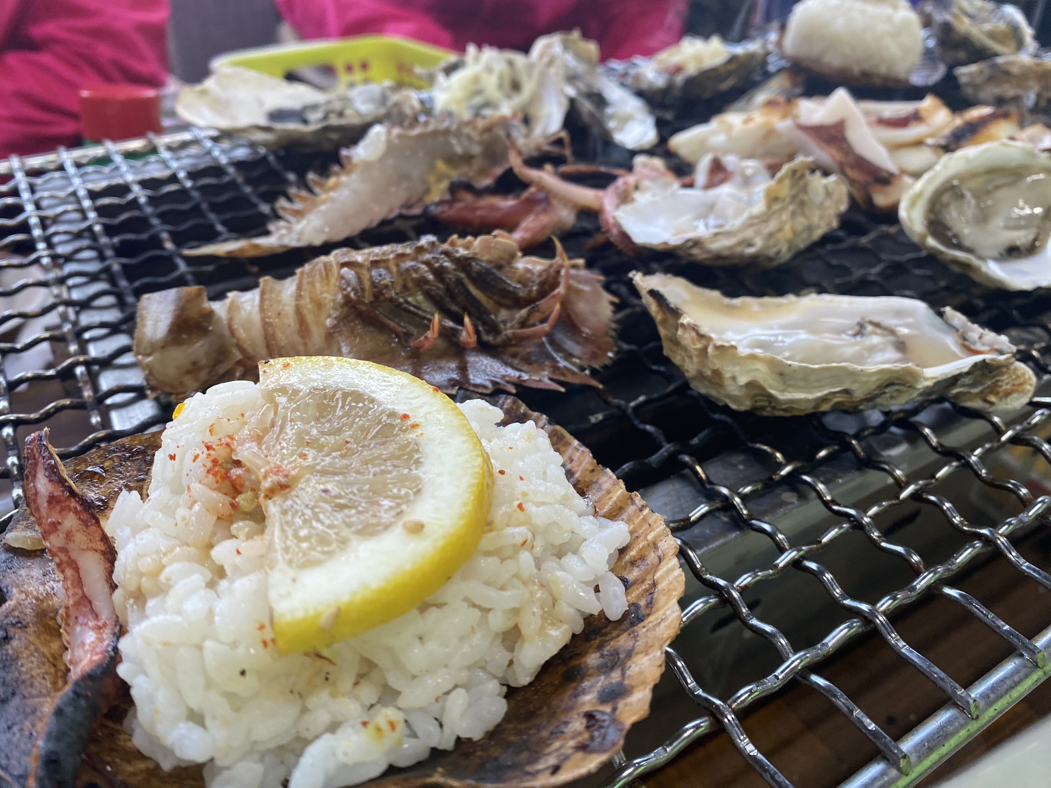 ホタテの貝殻に盛ったご飯、レモンを添えて。奥には牡蠣が並ぶ