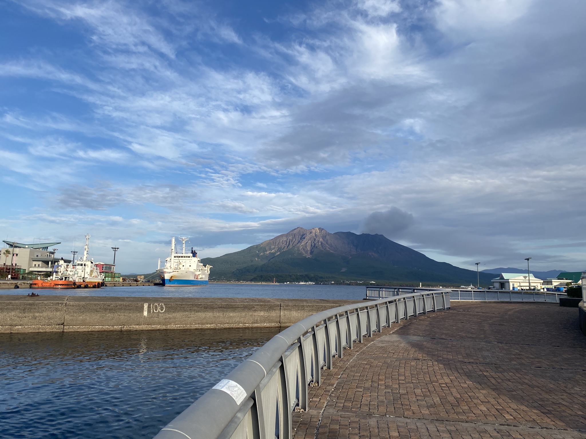 Kagoshima port white cargo ship Sakurajima volcano backdrop clear sky
