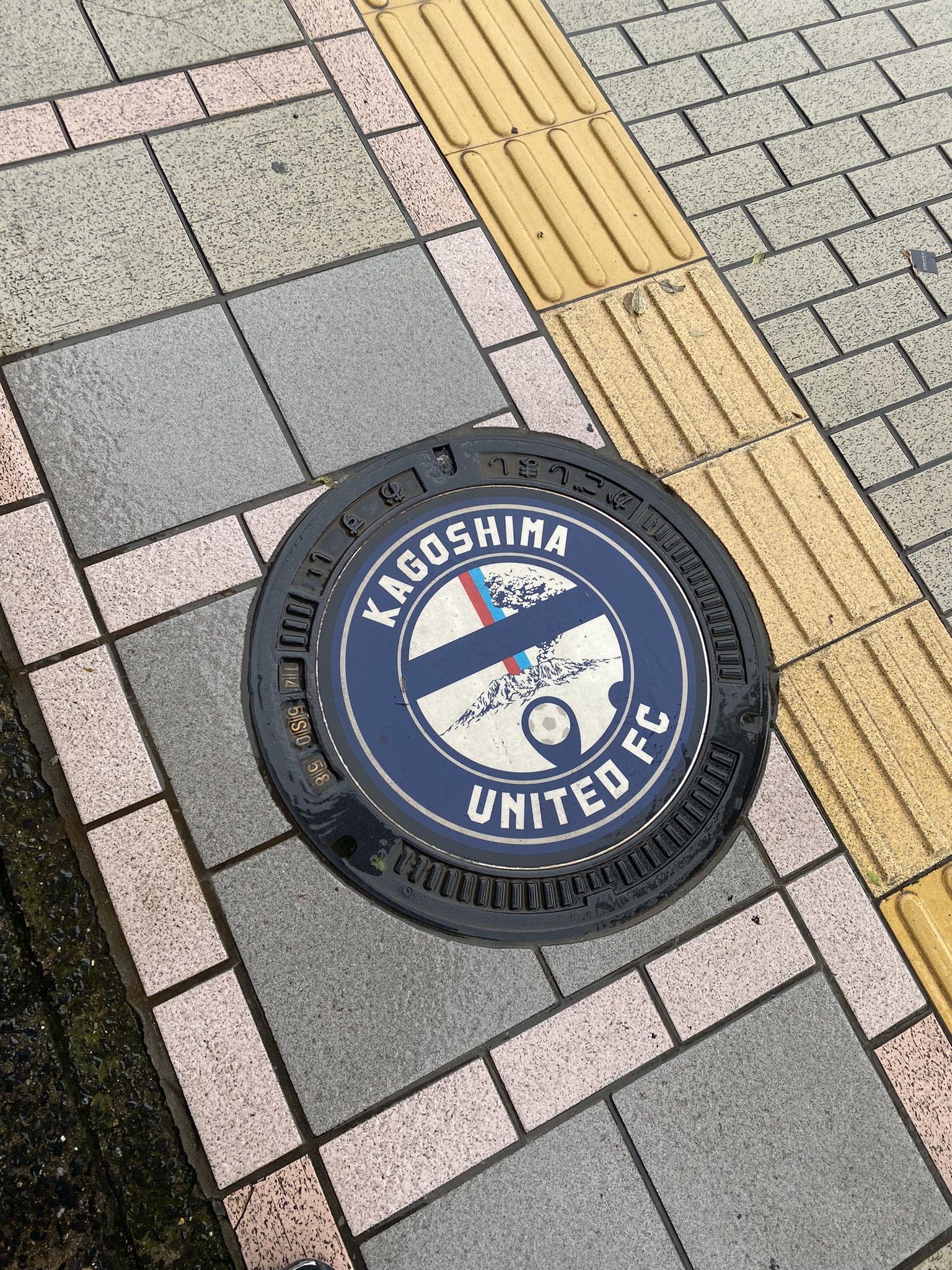 Kagoshima United FC branded manhole cover blue design with club logo on street