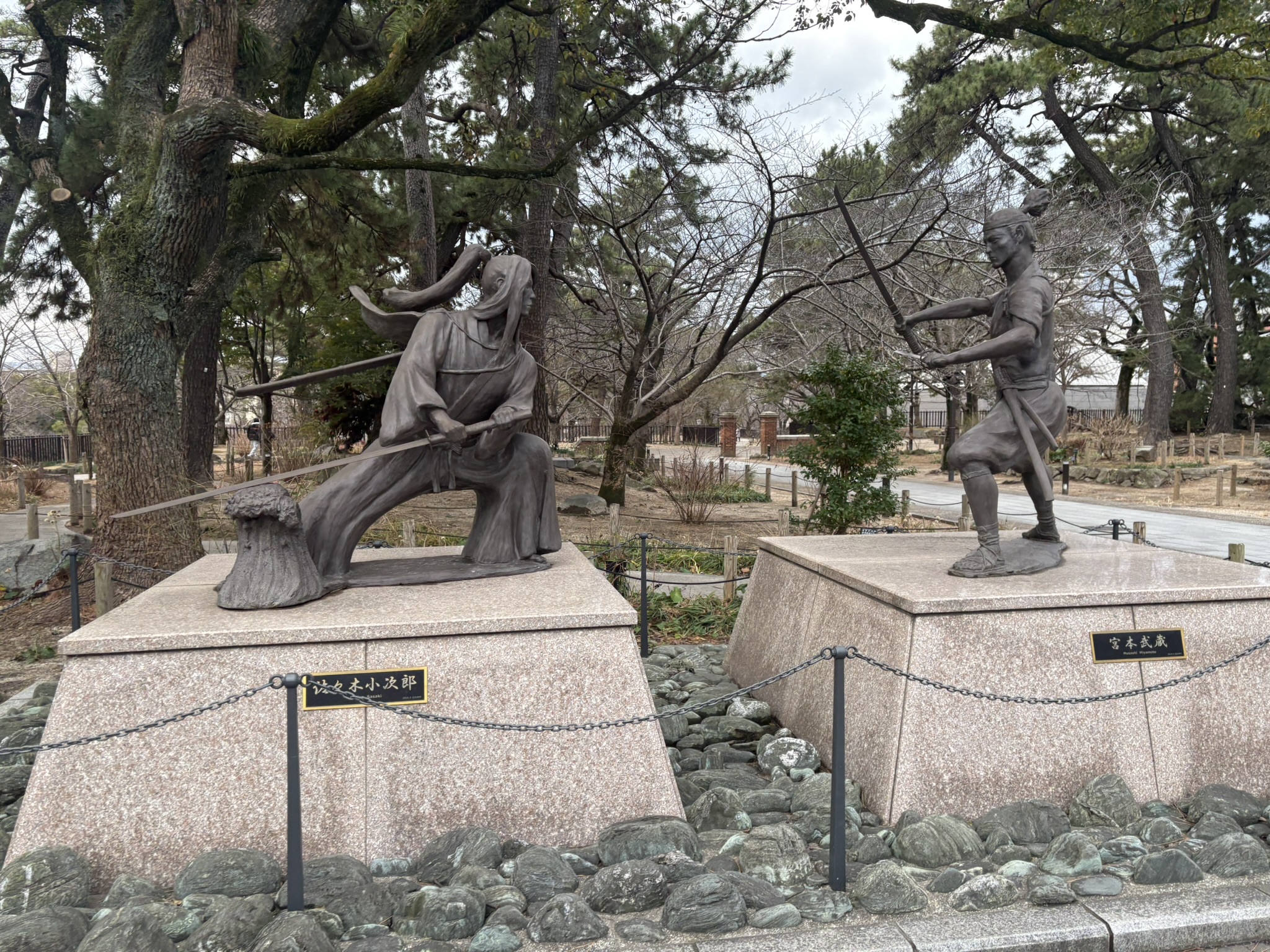 小倉城庭園の松林の中に立つ、刀を構えた武士の銅像