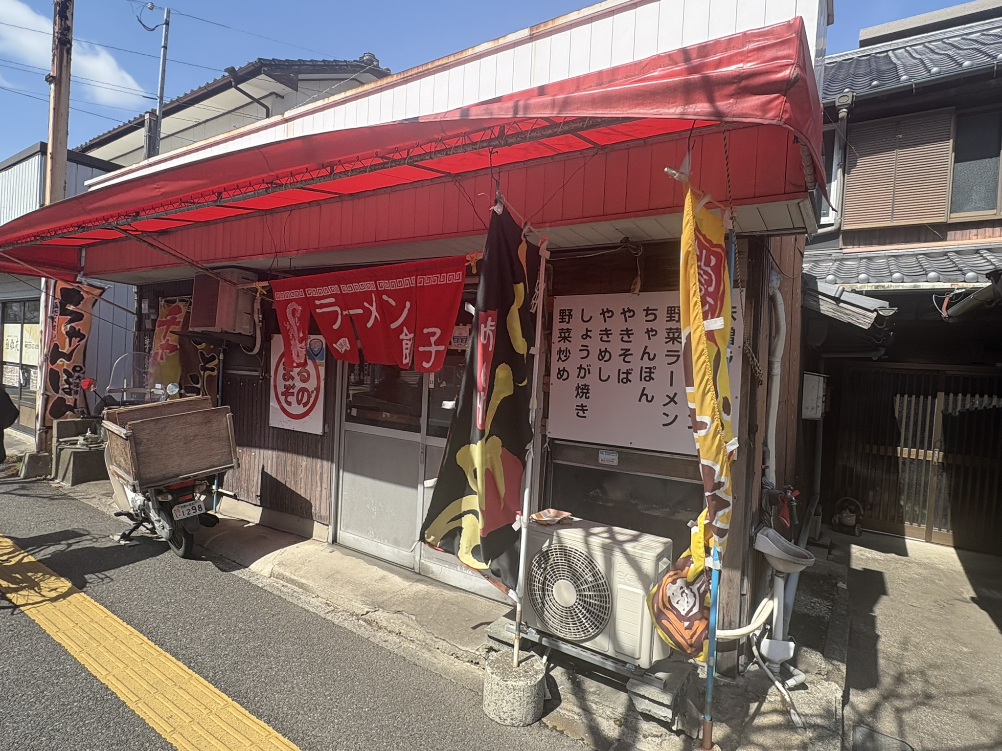まるぞのラーメンの外観。赤い屋根とのぼり旗が目立つ食堂
