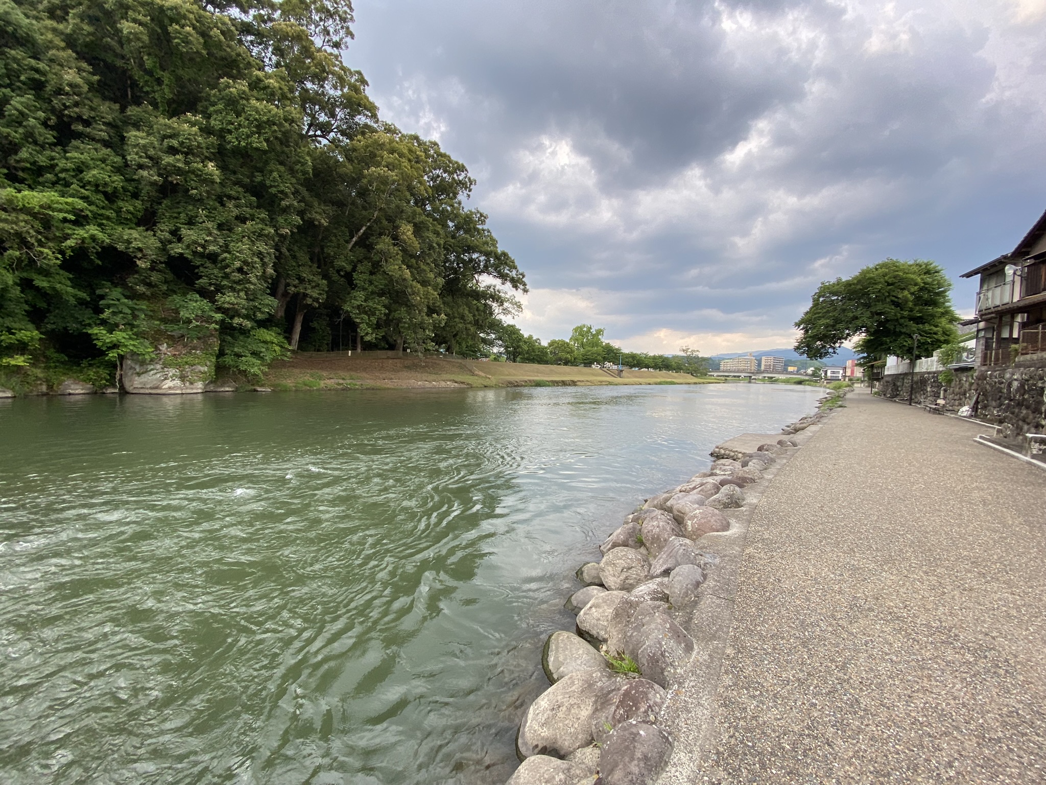 Mikuma River riverside promenade in Hita city with green trees and calm water