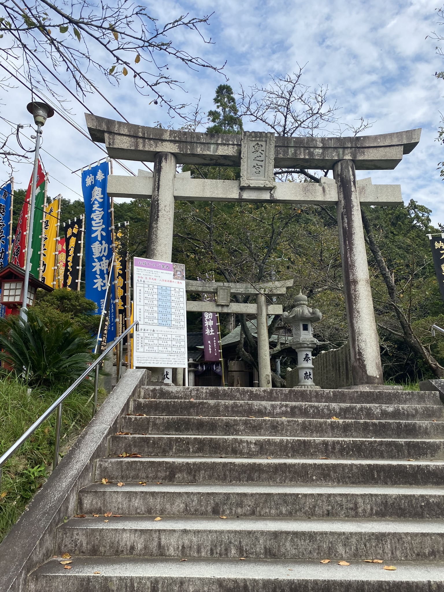 Miyajidake Jinja sub-shrine Fudo stone torii gate with colorful prayer flags