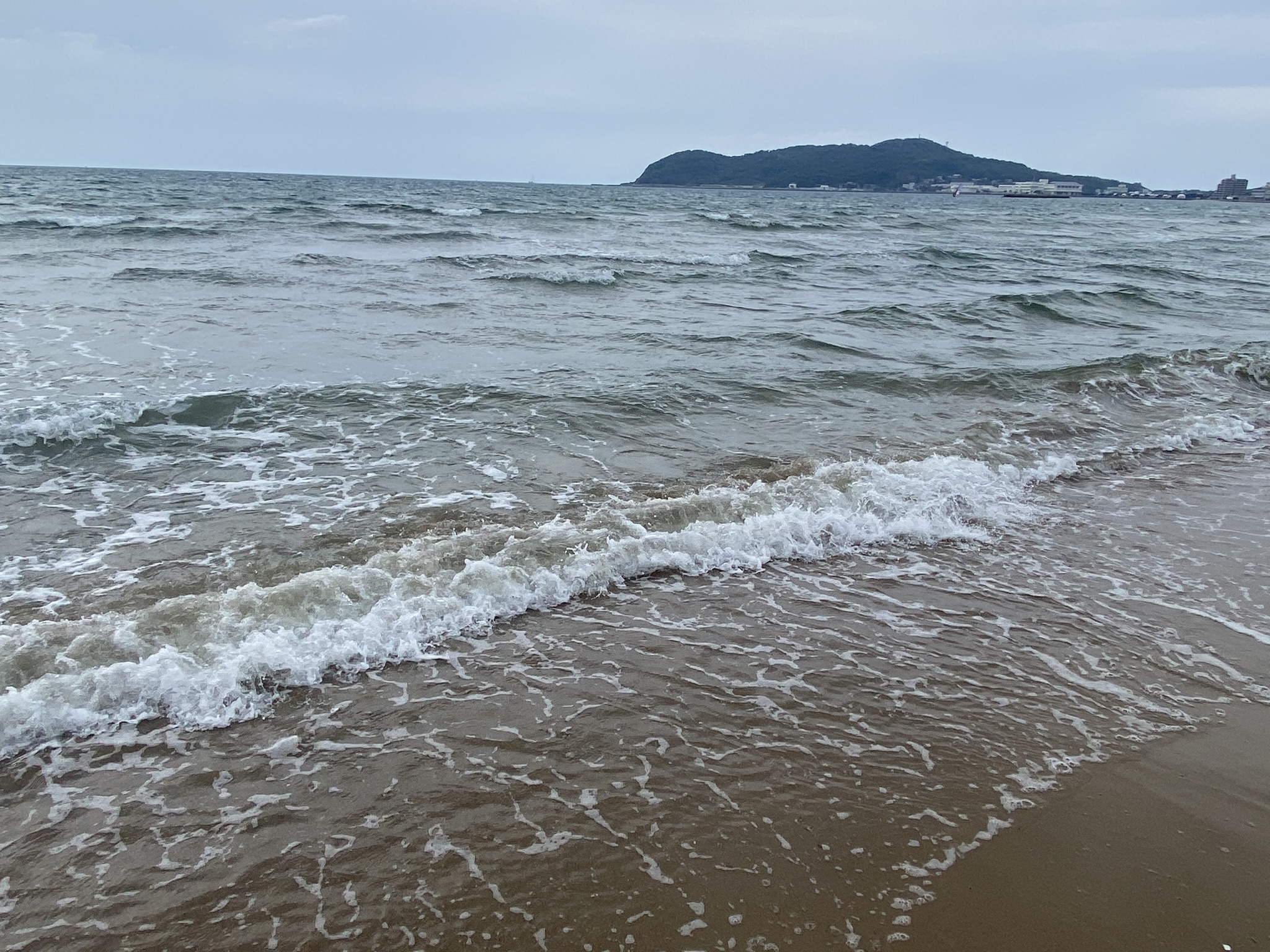 Miyajihama beach with waves and Shikanoshima island visible in the distance