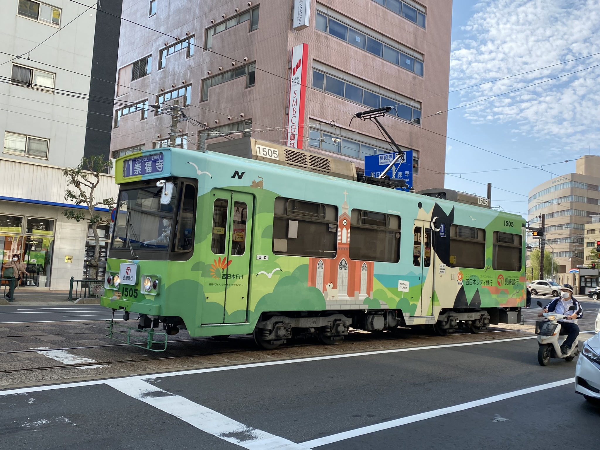Nagasaki city tram with green wrapping design running on street