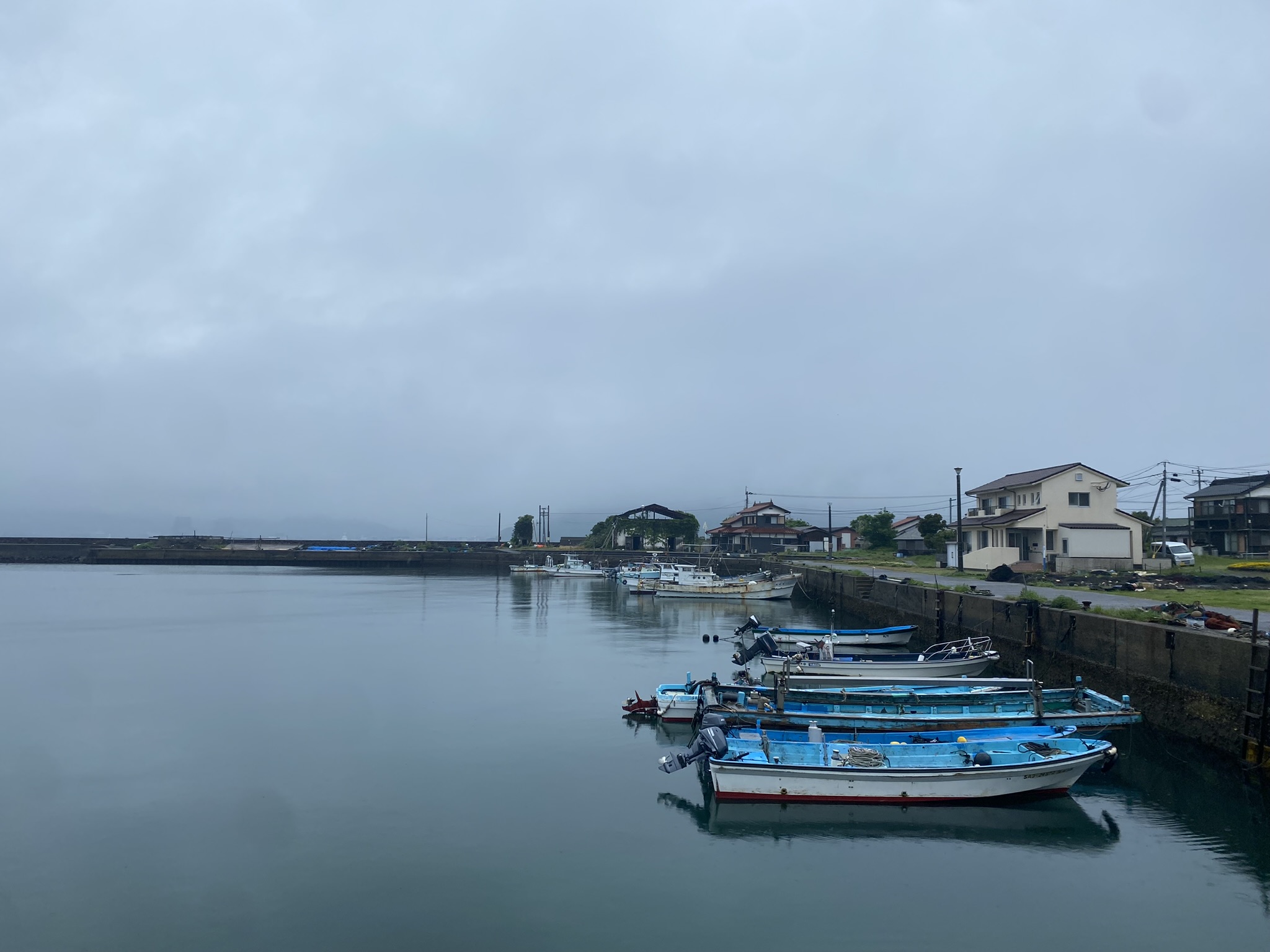 Takarashima island fishing port blue boats moored harbor houses cloudy sky calm sea